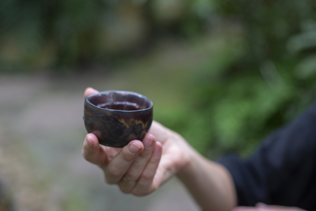 Pouring tea into traditional black cups during a ceremony