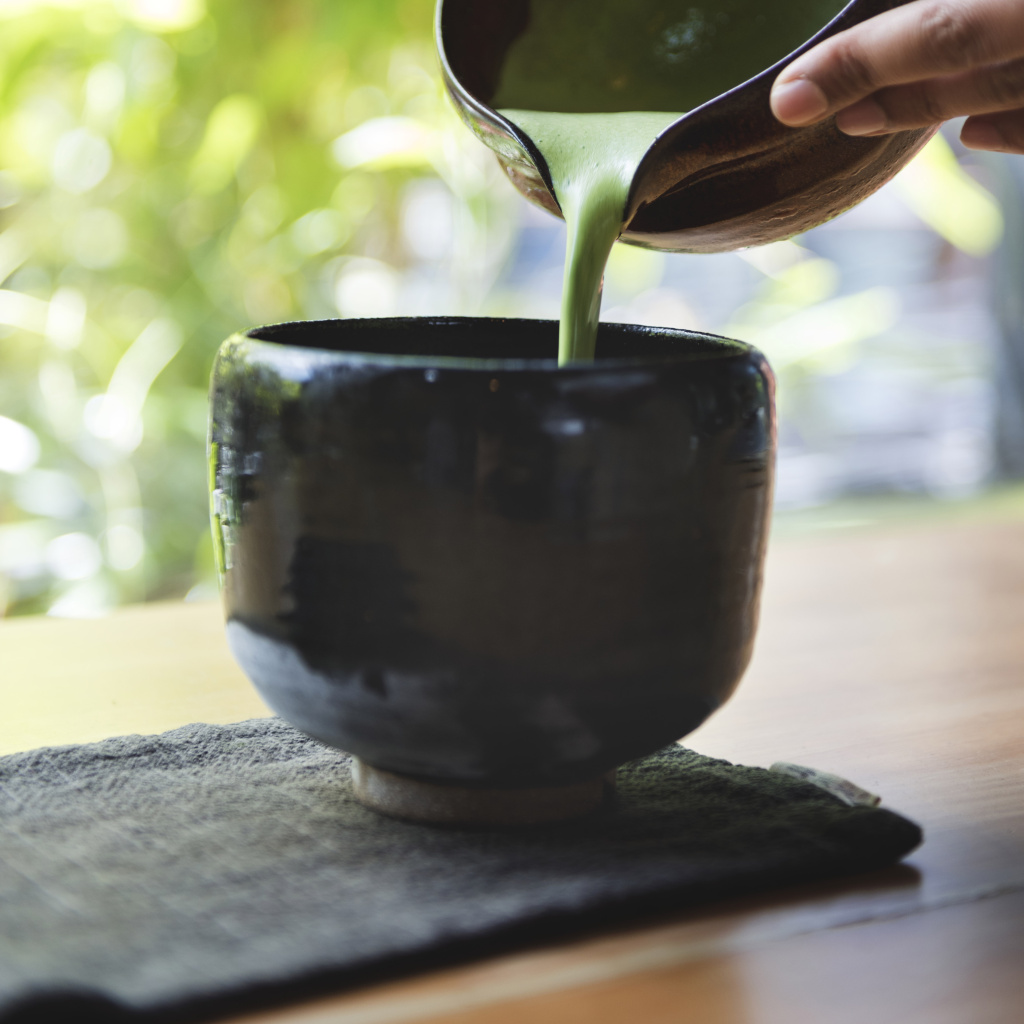 Preparing Japanese matcha tea in a black bowl